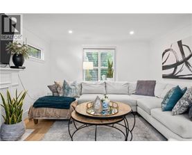 A living room with a white couch, a coffee table, and a window with blinds.