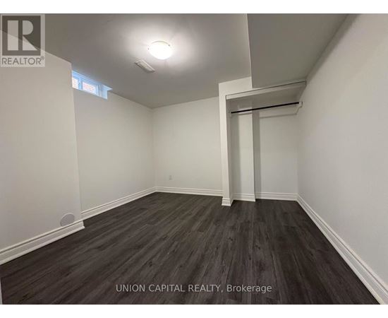 A room with wooden flooring and white walls, with a doorway leading to another room.