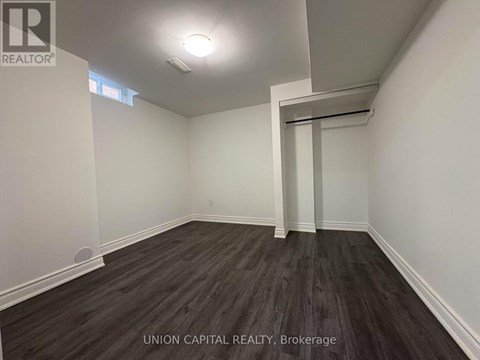A room with wooden flooring and white walls, with a doorway leading to another room.