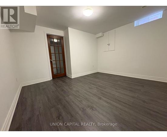 A room with wooden flooring and a door at the end.