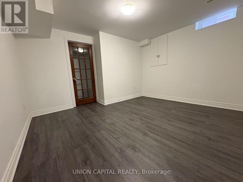 A room with wooden flooring and a door at the end.