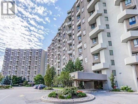 A large apartment complex with a parking lot in front.