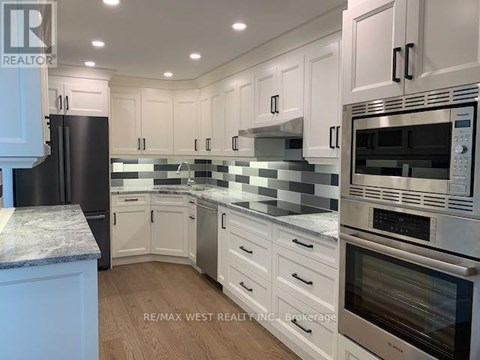 A kitchen with white cabinets and a black refrigerator.