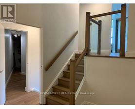 A staircase with a wooden handrail and white walls.