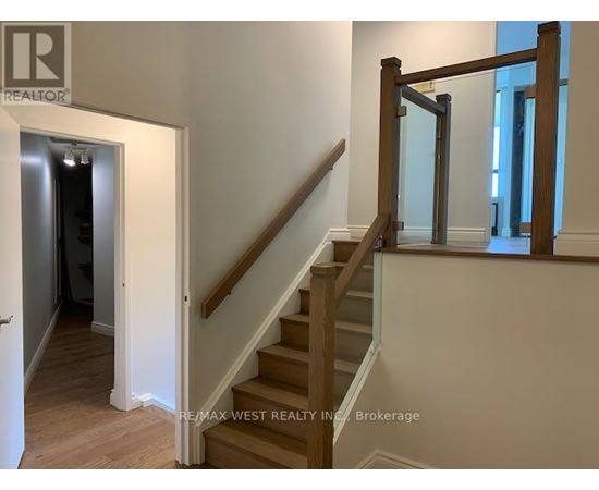 A staircase with a wooden handrail and white walls.