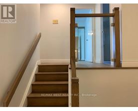 A staircase with a wooden handrail and steps leading to a bright room.