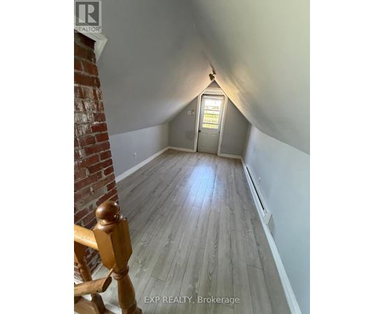 A hallway with wooden floors and a brick wall on the left.