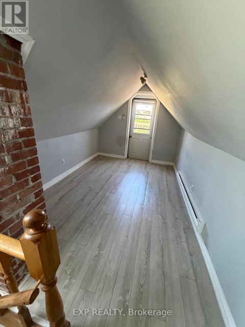 A hallway with wooden floors and a brick wall on the left.