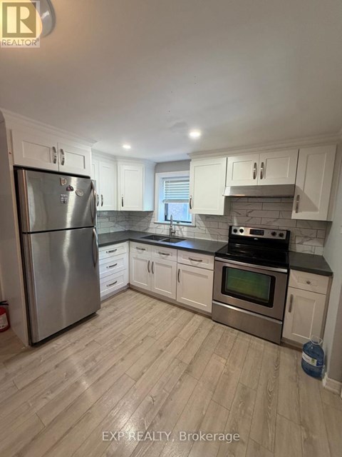 A kitchen with white cabinets and a stainless steel refrigerator.
