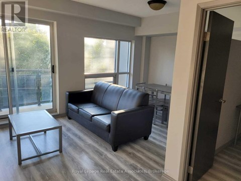 A black leather sofa sits in a living room with a glass table in front of it.