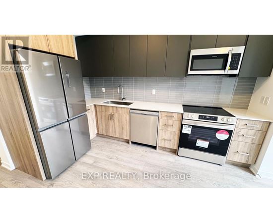A kitchen with a refrigerator, oven, and microwave.