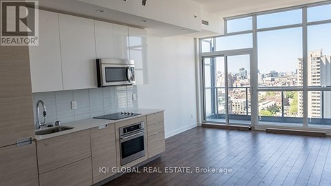 A kitchen with a microwave, sink, and oven with a view of the city.