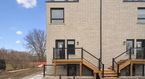 A brick building with a black railing and a wooden staircase.