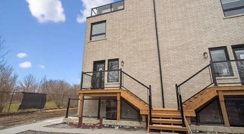 A modern two-story building with a balcony and stairs leading to the upper level.