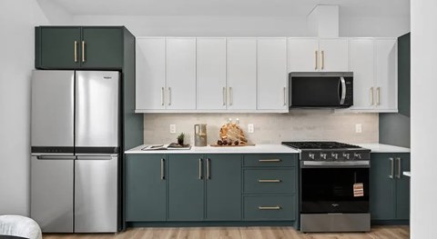 A kitchen with green cabinets and a stainless steel refrigerator.