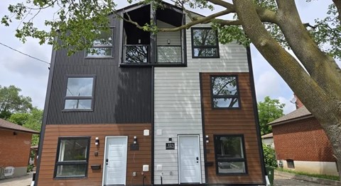 A modern two-story house with a mix of dark and light wooden siding.