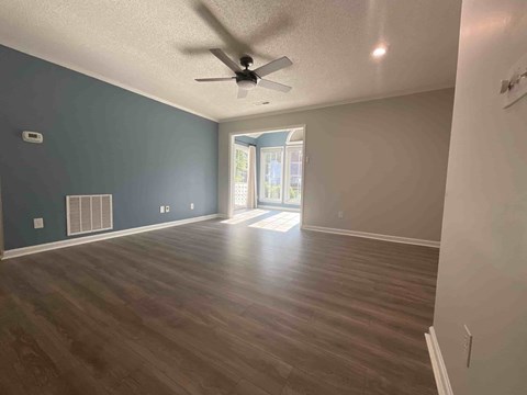 A room with a ceiling fan and wooden flooring.