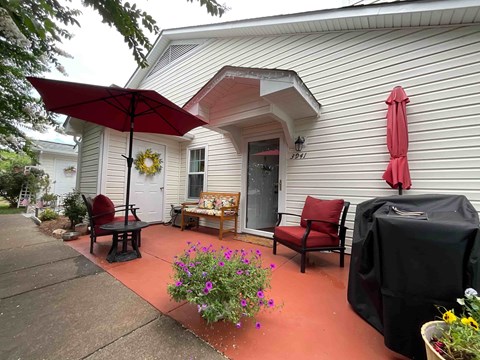 A patio with a table, chairs, and an umbrella.