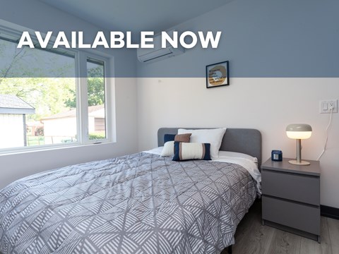 A bedroom with a bed, nightstand, and lamp is available now.