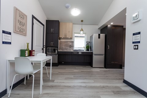 A kitchen with a white table and chairs and a fridge.