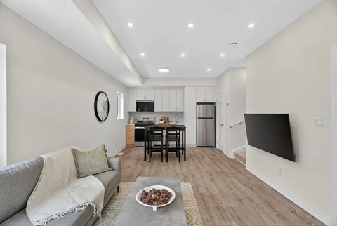 A modern living room with a grey sofa and a wooden floor.