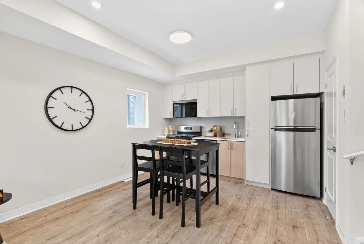 A kitchen with a table and chairs and a clock on the wall.