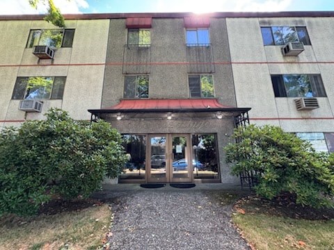 A building with a red awning and a gravel driveway in front.
