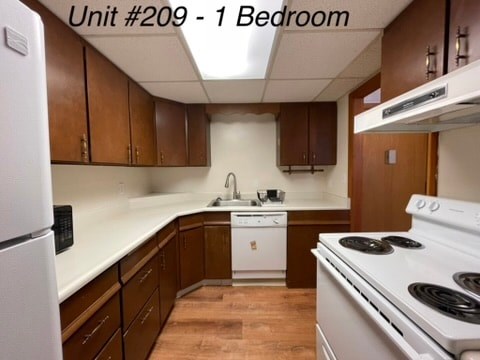 A kitchen with brown cabinets and white appliances.