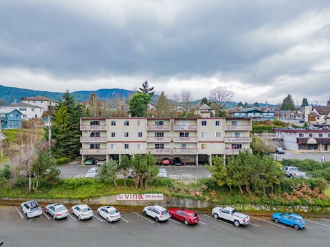 A parking lot with cars and a multi-story building in the background.