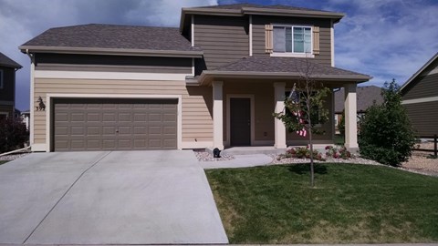 A house with a garage and a flag on the front lawn.