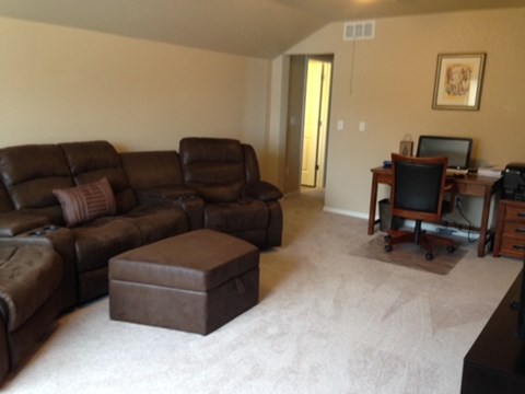 A living room with a brown leather couch and ottoman.