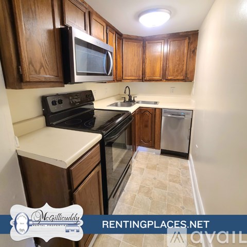 A kitchen with wooden cabinets and black appliances is for rent.