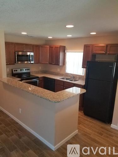 A kitchen with wooden cabinets and a black refrigerator.