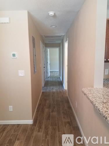 A hallway with wood flooring and a carpeted area.