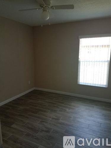 A room with a ceiling fan and a window with blinds.