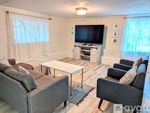 A living room with a grey couch, a white coffee table, and a television.