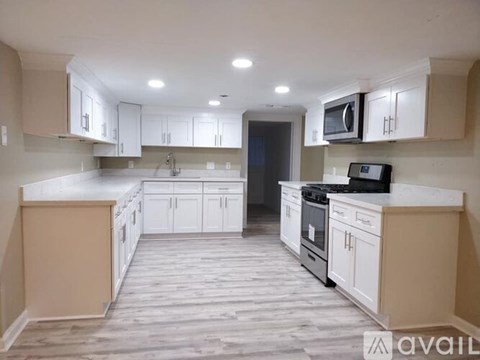 A kitchen with white cabinets and a wooden floor.