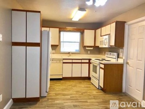 A kitchen with white appliances and wooden cabinets.