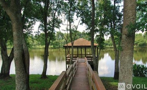 A gazebo is situated on a wooden pier in the middle of a lake.