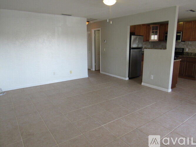 A spacious living room with a kitchen in the background.