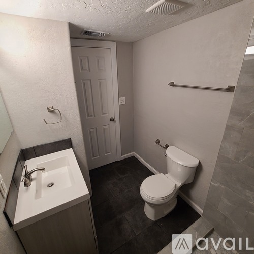 A bathroom with a toilet, sink, and a door.