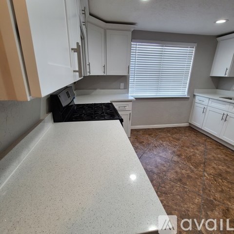 A kitchen with a black stove top oven and white cabinets.