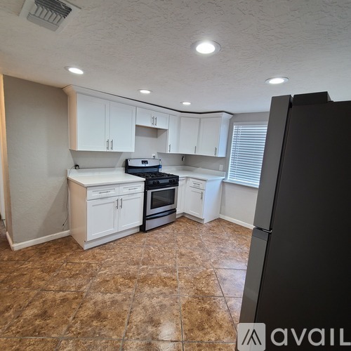 A kitchen with white cabinets and a black refrigerator.