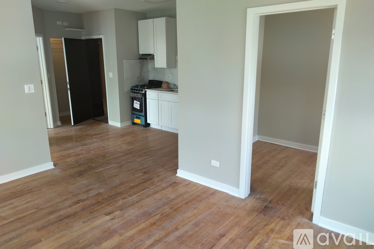 A kitchen area with a black refrigerator and wooden floors.