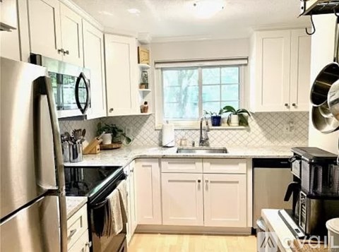 A kitchen with white cabinets and a stainless steel refrigerator.