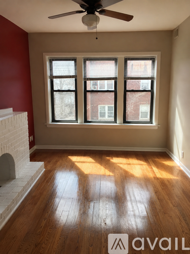 A room with a fireplace and a window with a view of a brick building outside.