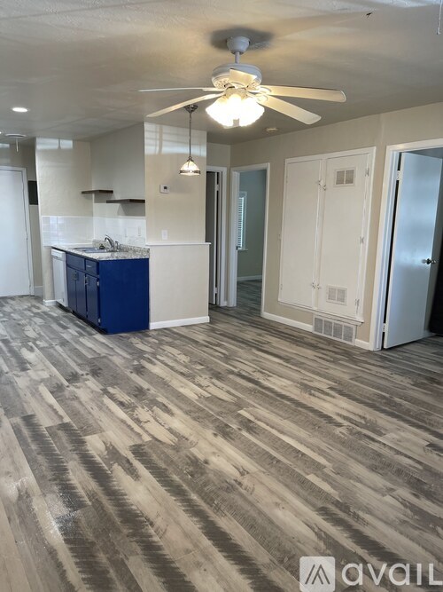 A room with a ceiling fan and a kitchen area.