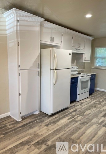 A kitchen with a white refrigerator and a white cabinet.