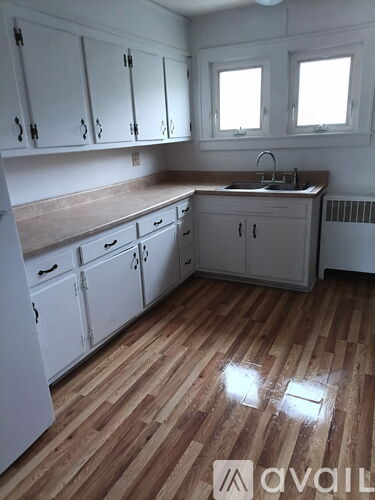 A kitchen with white cabinets and wooden floors.