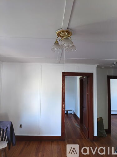 A room with a wooden floor and a chandelier hanging from the ceiling.